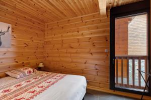 a bedroom with wooden walls and a bed and a window at Chalet Les Lupins in Les Angles
