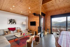 a living room with a couch and a table and a tv at Chalet Les Lupins in Les Angles