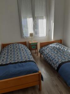 una camera da letto con due letti e un tavolo con una lampada di L'Avre de Roye a Roye