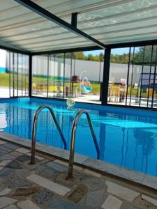 a swimming pool with blue water and glass windows at Gyps Vikendica with Swimming Pool and Sauna 2 in Tuzla