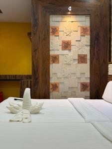 a bedroom with a white bed with a tile wall at Vaishali Deluxe Comfort in Tumkūr