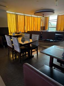 a dining room with a table and chairs and yellow curtains at Vaishali Deluxe Comfort in Tumkūr