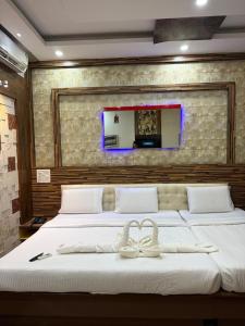 a bedroom with a large bed with two white beds at Vaishali Deluxe Comfort in Tumkūr +24 photos