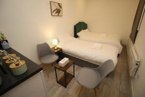 Habitación pequeña con 2 camas, escritorio y sillas. en AMD Hotel Modern Comfort in the Heart of Sutton SM1, en Sutton