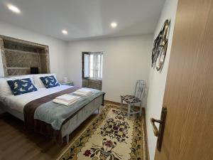 a bedroom with a bed with blue pillows and a chair at Vila Mena by Trip2Portugal in Gonçalo Bocas