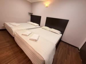 two beds in a room with white sheets and towels at Swing & Pillows - Dataran Nilai in Nilai