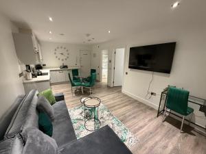 a living room with a couch and a table with green chairs at Kings Lodge By Nivaas 2 in Reading