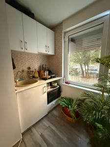 una cucina con mobili bianchi, un lavandino e una finestra di Green Apartment a Bucarest