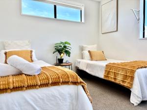 een slaapkamer met twee bedden en een raam bij Travellers' dream steps from shops and close to Airport in Christchurch
