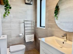 a bathroom with a sink and a toilet and a mirror at Travellers' dream steps from shops and close to Airport in Christchurch +28 photos