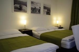 two beds in a hotel room with pictures on the wall at Apartments Santis10 in Baška