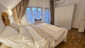 a bedroom with a white bed with a window at Evie's Tree House in Dragomirna