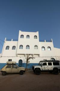 two cars parked in front of a large building at Ifni Sunset in Sidi Ifni +41 photos