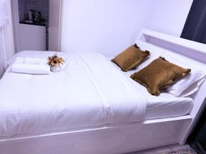 a white bed with pillows and a vase of flowers on it at Beautiful and Spacious 1 Bedroom Apartment in Erith