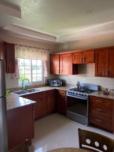 a kitchen with wooden cabinets and a stove top oven at Cozy Retreat in Gated Portmore Country Club in Portmore +3 photos