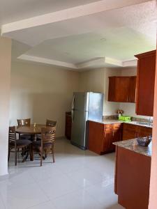a kitchen with a table and a stainless steel refrigerator at Cozy Retreat in Gated Portmore Country Club in Portmore +2 photos