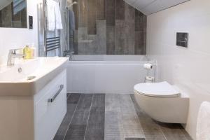 a white bathroom with a tub and a toilet and a sink at Sunset View in Innellan +24 photos