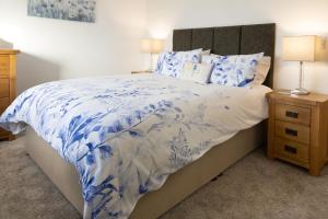 a bedroom with a blue and white bed with a night stand at Sunset View in Innellan