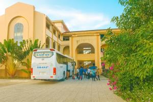 a white bus parked in front of a building at Hồng Ân Motel Quảng Trị in Quảng Trị