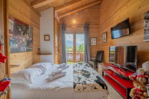 Un dormitorio con una cama grande y un televisor. en Alpine Luxury Chalet Pool & Jacuzzi, en Cordon