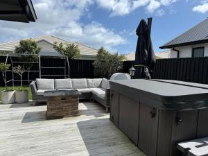 a patio with a couch and a table and an umbrella at Beach days and cozy stays - sleeps seven in Tauranga +2 photos