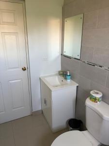 a bathroom with a toilet and a sink and a mirror at Cozy Retreat in Gated Portmore Country Club in Portmore