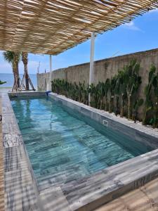 a large swimming pool with a wooden roof at Villa Biển Vàng Beach Front in Bình Sum