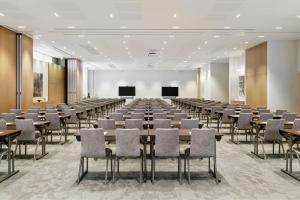 a large room with tables and chairs and a screen at AC Hotel by Marriott Vilnius in Vilnius