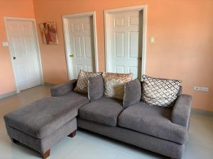 a couch and a chair in a living room at Cozy Retreat in Gated Portmore Country Club in Portmore +1 photo