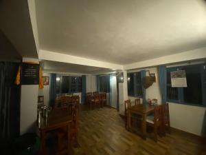 a dining room with wooden tables and chairs and windows at Hotel aagan cafe and resturant in Astam