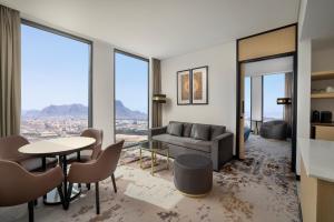 a living room with a couch and a table and chairs at Doubletree by Hilton Madinah Gate in Al ‘Awālī