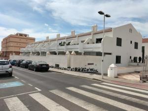 a white building with cars parked on the side of a street at Bungalow Médano in El Médano