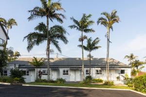 a white house with palm trees in front of it at The Notebook Hotel in Port Shepstone