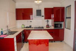 a kitchen with red cabinets and a white counter top at Pwj Realty Apartments in Lekki