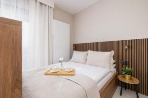 a bedroom with a white bed with a wooden table at Elegant Studios in Katowice with Gym, Sauna & Cinema by Noclegi Renters in Katowice