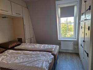 two beds in a small room with a window at Kaapsduun 06 in Nes