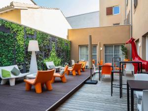 a deck with chairs and tables on a building at Mercure Libourne Saint Emilion in Libourne