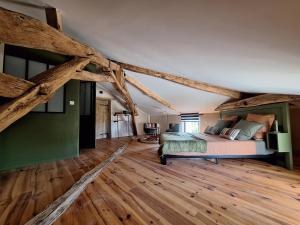 a bedroom with a bed in a room with wooden floors at Le pigeonnier de Pauly in Mirabel +35 photos