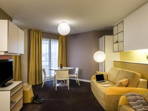 a living room with a couch and a table with a laptop at AppartHotel Mercure Paris Boulogne in Boulogne-Billancourt