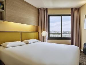 a bedroom with a large white bed and a window at AppartHotel Mercure Paris Boulogne in Boulogne-Billancourt