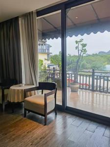 桂林市にあるSecret Garden Lakefront Hotel 连住两晚享高铁站免费接站のテーブルと椅子、大きな窓が備わる客室です。