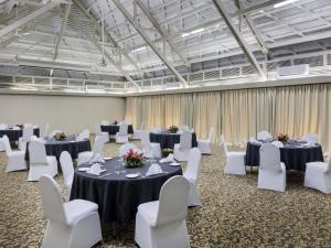 a banquet hall with tables and white chairs at Novotel Nadi in Nadi