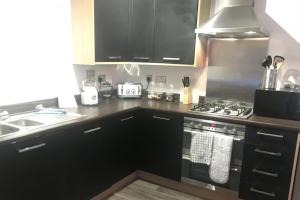 ニュートン・アボットにある2-Bed Apartment Sleeps 4 with Gardenのキッチン(黒いキャビネット、コンロ付)