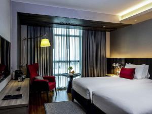 a hotel room with a large bed and a red chair at Pullman Bangkok King Power in Bangkok