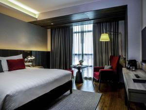 a hotel room with a bed and a chair at Pullman Bangkok King Power in Bangkok +142 photos