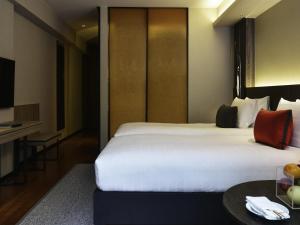 a hotel room with a large bed and a table at Pullman Bangkok King Power in Bangkok