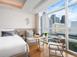 a bedroom with a bed and a desk and a window at Pullman Bangkok King Power in Bangkok