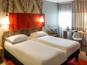 a hotel room with a large bed and a desk at ibis Birmingham Airport Terminal Building - NEC in Bickenhill +47 photos