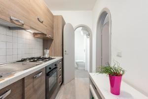 a kitchen with wooden cabinets and a pink potted plant at Domus Elisae - Taormina in Taormina