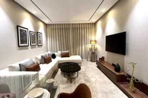 ein Wohnzimmer mit einem weißen Sofa und einem Fernseher in der Unterkunft Anfa The Address - By AppartAli in Anfa-Supérieur